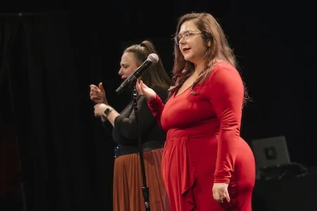 Coby Jones in a red dress, giving a speech